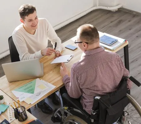Trabajador con discapacidad firmando documentación laboral junto a un profesional.